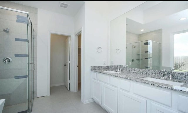 bathroom with double vanity, a stall shower, tile patterned flooring, and a sink