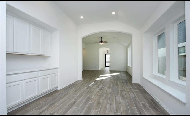 interior space featuring arched walkways, wood finish floors, baseboards, and recessed lighting