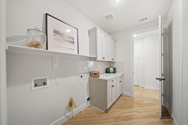 5715 Caracara St, Manvel, TX 77578 - washroom featuring hookup for a washing machine, light wood-style flooring, hookup for an electric dryer, visible vents, and cabinet space