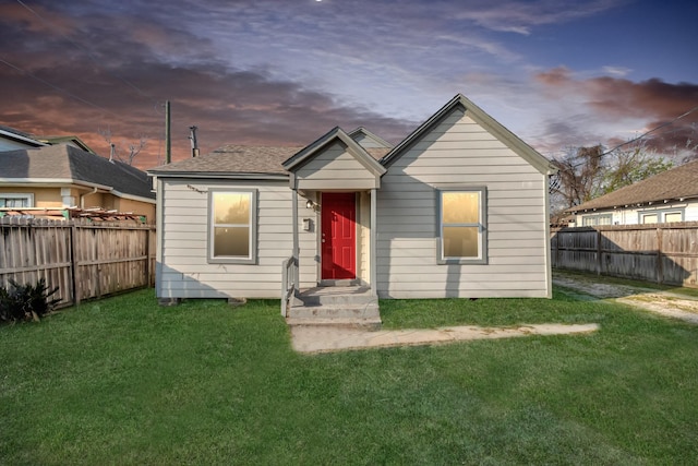 rear view of house featuring a yard and a fenced backyard