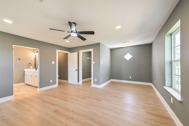 unfurnished bedroom with baseboards, ensuite bathroom, a spacious closet, light wood-style floors, and recessed lighting