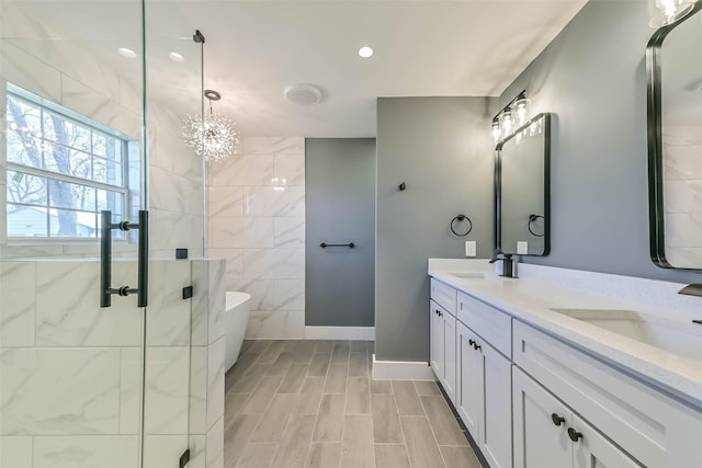 bathroom with double vanity, a soaking tub, a shower stall, and a sink