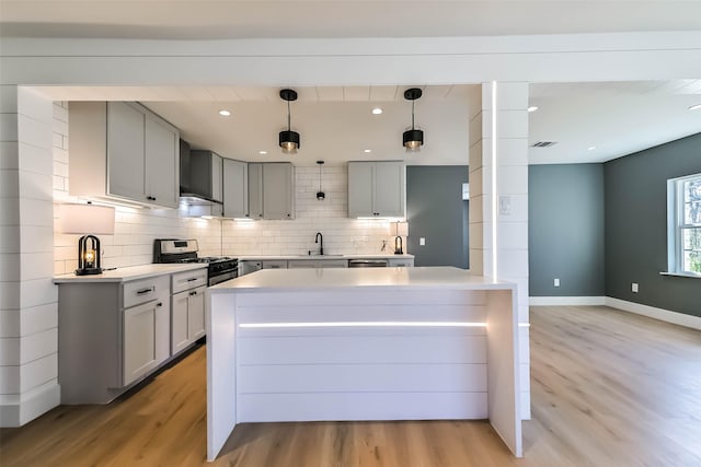 kitchen with gas range, tasteful backsplash, light wood-style floors, and a sink