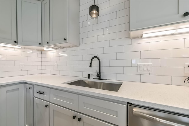 kitchen with light stone countertops, stainless steel dishwasher, tasteful backsplash, and a sink