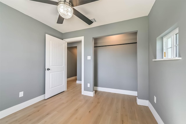 unfurnished bedroom with a closet, wood finished floors, visible vents, and baseboards