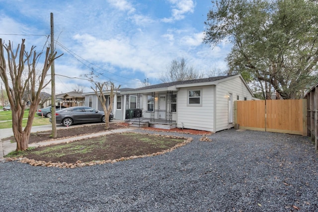 view of front of house with covered porch, driveway, and fence