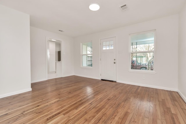 foyer with baseboards, wood finished floors, visible vents, and a healthy amount of sunlight