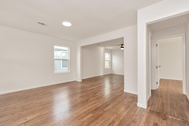 unfurnished room with light wood finished floors, a ceiling fan, visible vents, and baseboards