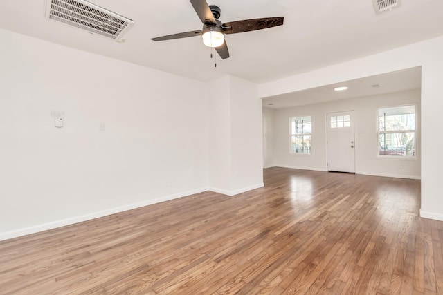 empty room featuring ceiling fan, wood finished floors, visible vents, and baseboards