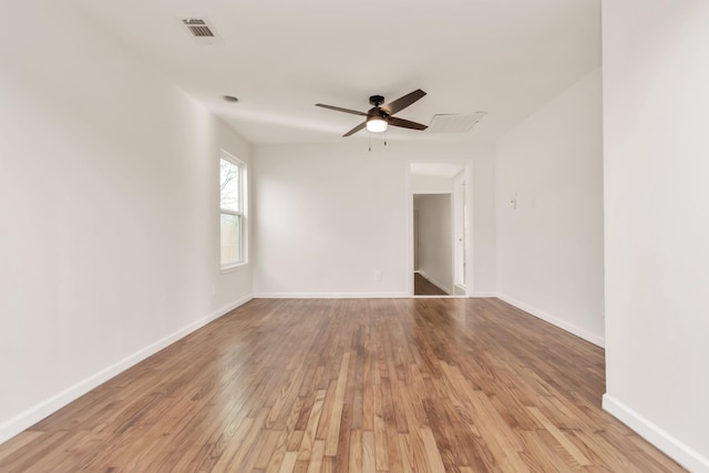 unfurnished room with a ceiling fan, visible vents, baseboards, and wood finished floors