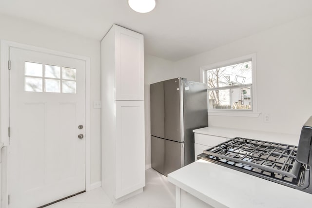 kitchen with white cabinets, light countertops, and freestanding refrigerator