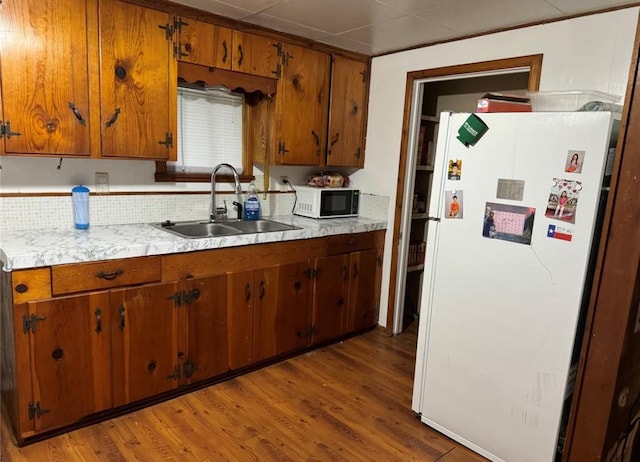 kitchen featuring light wood finished floors, light countertops, a sink, and freestanding refrigerator