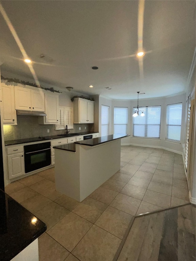 kitchen with dark countertops, a kitchen island, under cabinet range hood, and black appliances