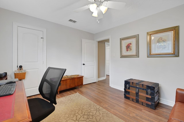 home office with visible vents, ceiling fan, baseboards, and wood finished floors