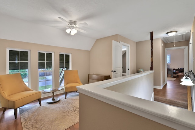 corridor featuring attic access, baseboards, vaulted ceiling, and wood finished floors