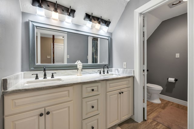 full bath featuring double vanity, wood finished floors, a sink, and toilet