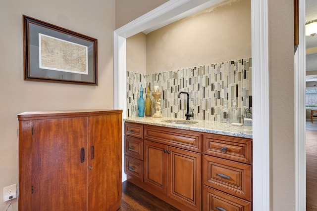 bar with tasteful backsplash, dark wood-style flooring, a sink, and wet bar