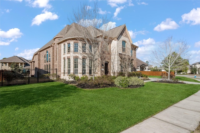 exterior space with brick siding, a lawn, and fence