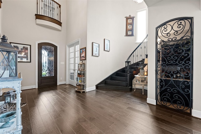 foyer featuring stairs, a high ceiling, wood finished floors, and baseboards