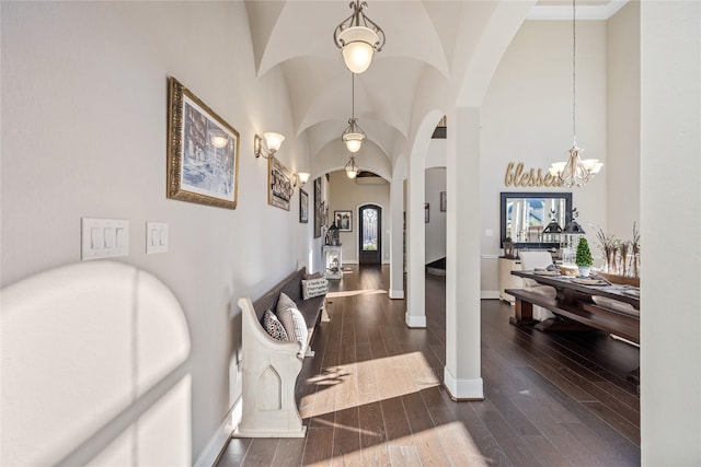 foyer entrance with baseboards, a high ceiling, arched walkways, and dark wood finished floors