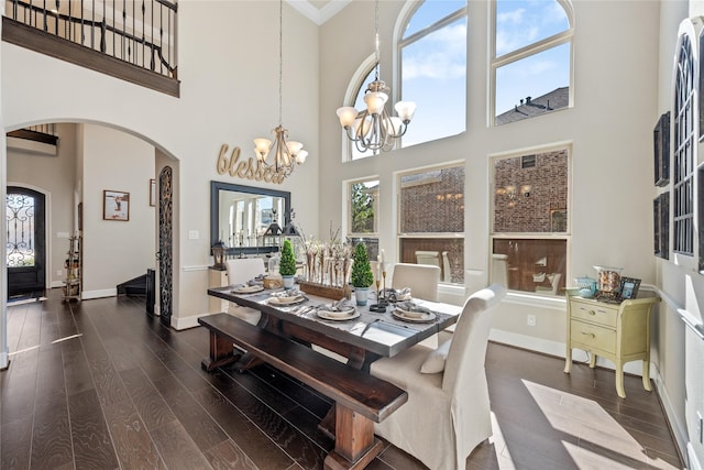 dining area with a wealth of natural light, arched walkways, and wood finished floors