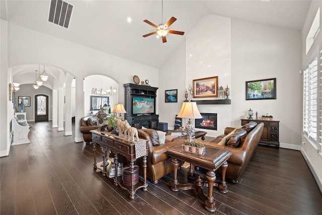 living area with arched walkways, a fireplace, wood finished floors, visible vents, and a healthy amount of sunlight