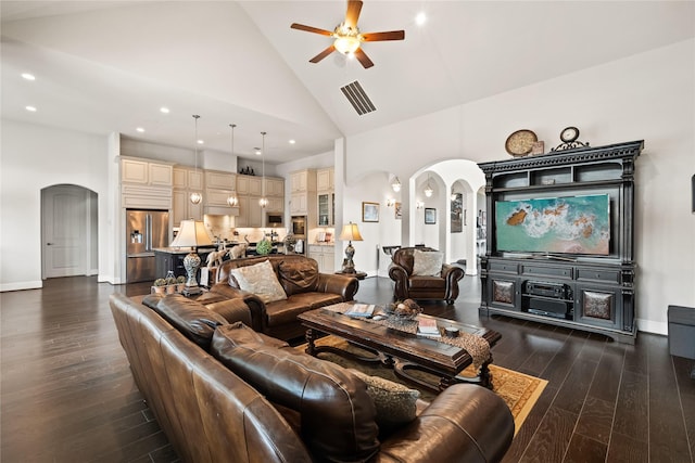 living area with arched walkways, high vaulted ceiling, dark wood-style flooring, visible vents, and a ceiling fan