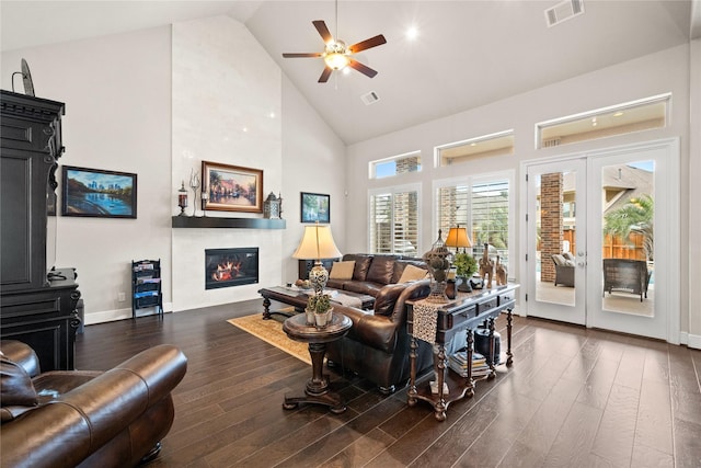 living area with dark wood-style flooring, a fireplace, visible vents, ceiling fan, and high vaulted ceiling