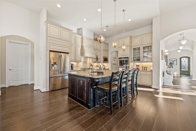 kitchen featuring arched walkways, stainless steel appliances, tasteful backsplash, and cream cabinets