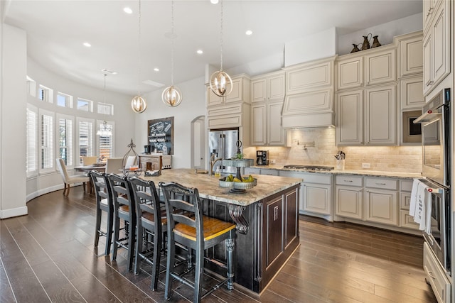 kitchen featuring tasteful backsplash, arched walkways, light stone counters, and cream cabinetry