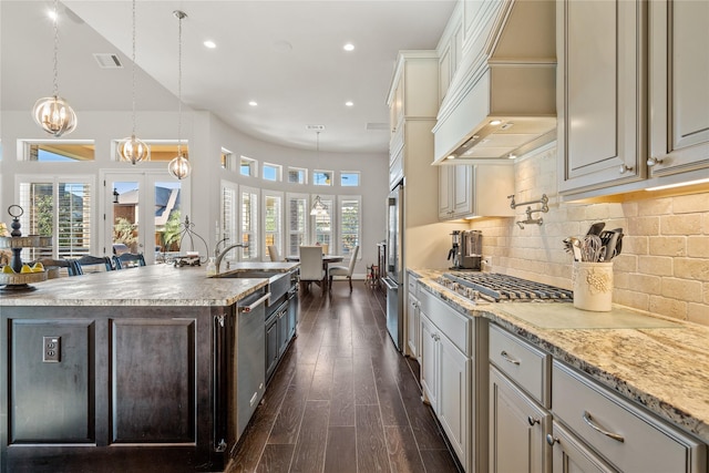 kitchen with dark wood-style floors, tasteful backsplash, appliances with stainless steel finishes, a sink, and premium range hood