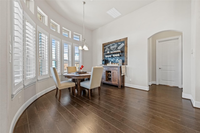 dining area featuring a chandelier, dark wood-type flooring, arched walkways, and baseboards