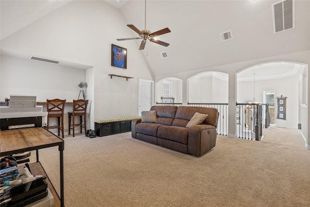 carpeted living area featuring high vaulted ceiling, arched walkways, and visible vents