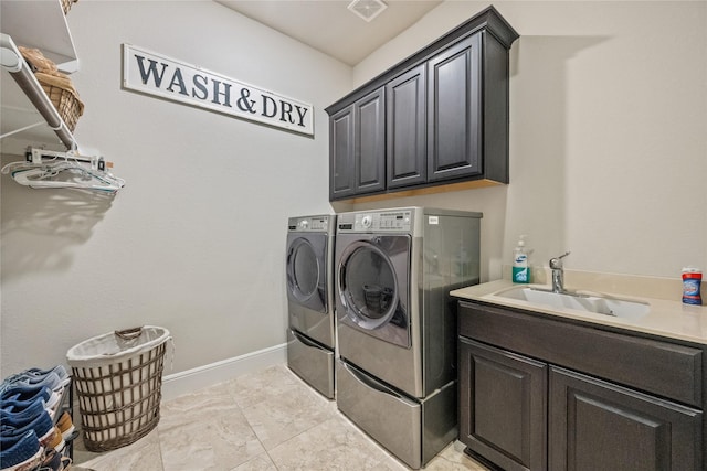 laundry room featuring washer and clothes dryer, visible vents, cabinet space, a sink, and baseboards