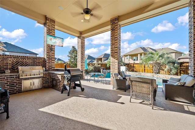 view of patio featuring an outdoor kitchen, grilling area, a fenced backyard, and a ceiling fan