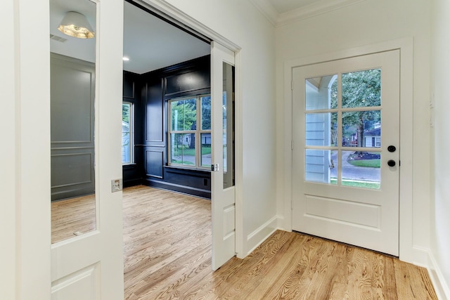 entryway with plenty of natural light, light wood-style flooring, and crown molding