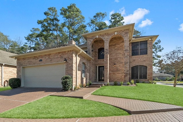 view of front of home featuring brick siding, driveway, a chimney, and a front lawn