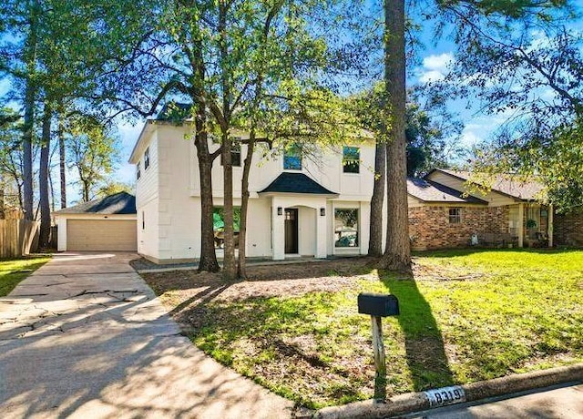 view of front of house with a front yard, a detached garage, and an outbuilding