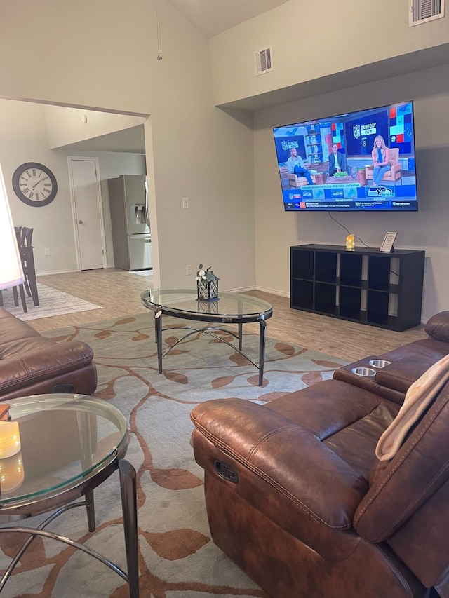 living room featuring lofted ceiling, visible vents, and baseboards