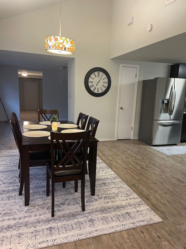 dining space featuring high vaulted ceiling, baseboards, and wood finished floors