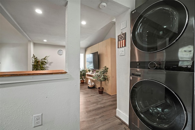 washroom featuring stacked washer / drying machine, laundry area, recessed lighting, and wood finished floors