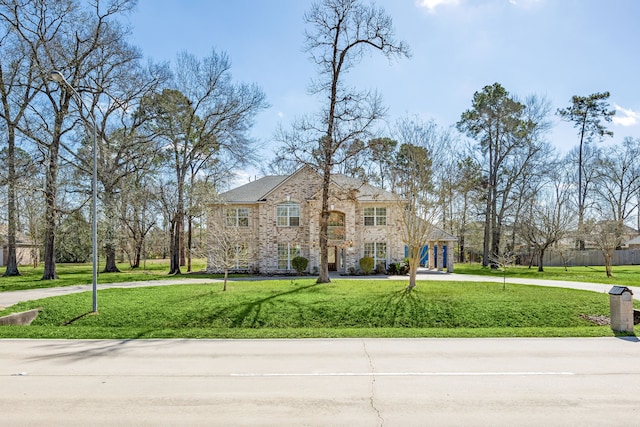 view of front of home featuring stone siding, a front lawn, and driveway