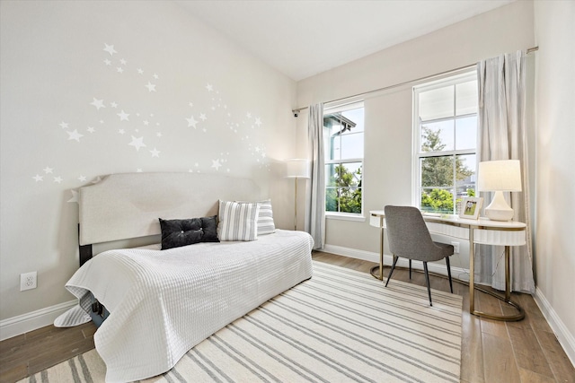 bedroom featuring vaulted ceiling, baseboards, and wood finished floors