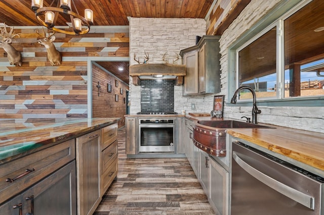 kitchen featuring decorative backsplash, wood ceiling, wood counters, appliances with stainless steel finishes, and a sink