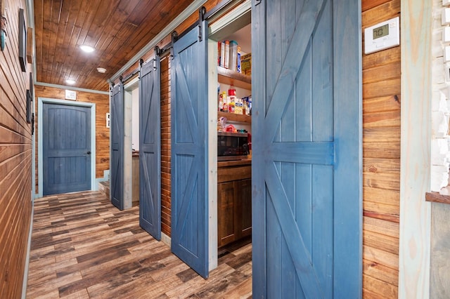 hallway with a barn door, wooden walls, wood ceiling, wood finished floors, and recessed lighting