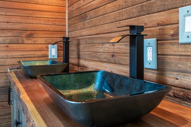 bathroom featuring a sink, wooden walls, and wood finished floors