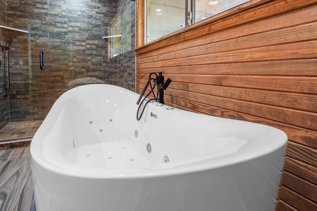 full bathroom featuring a freestanding bath, a shower stall, and tile walls