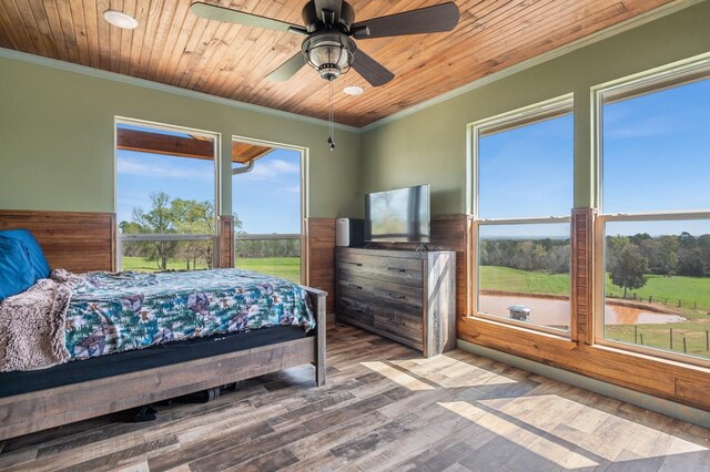 bedroom with a wainscoted wall, wood ceiling, ceiling fan, ornamental molding, and wood finished floors