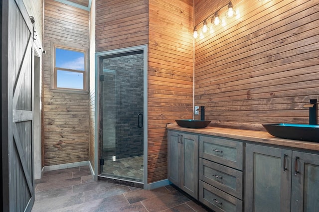 bathroom featuring a shower stall, a sink, wooden walls, and stone tile floors