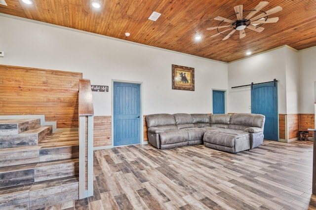 living area with wood ceiling, a barn door, wood finished floors, and wainscoting